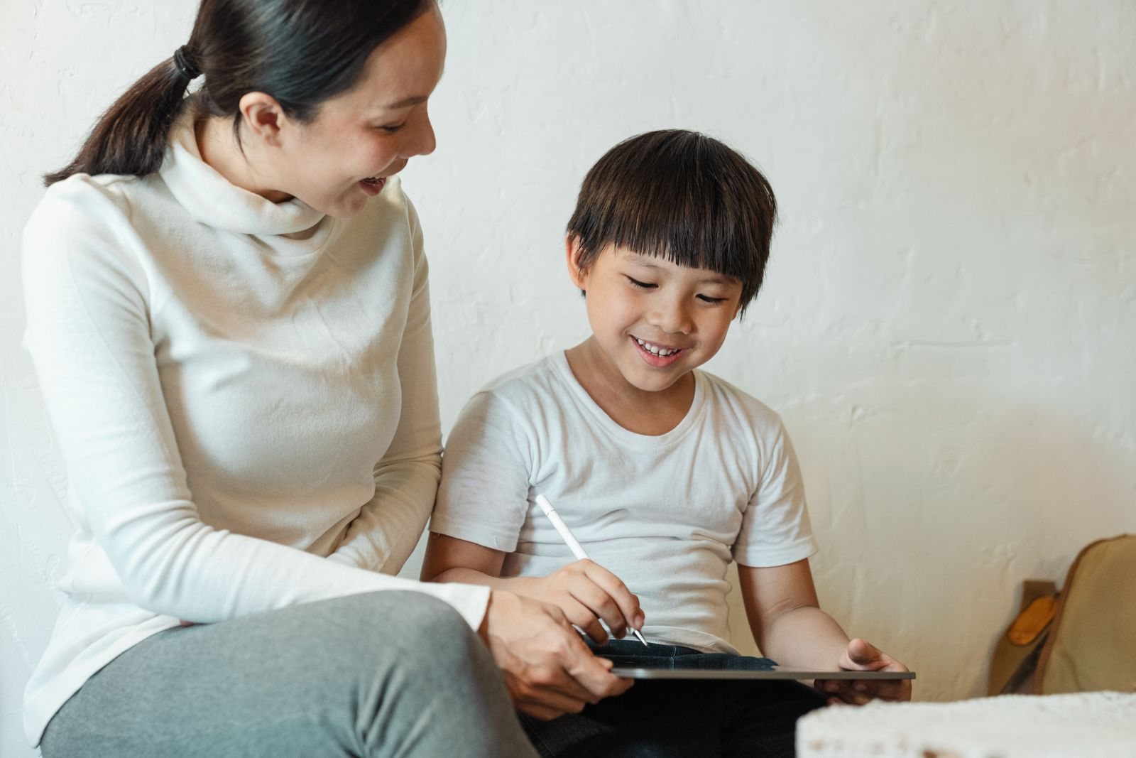 Uma adulta e uma criança partilham a atenção num tablet em casa.